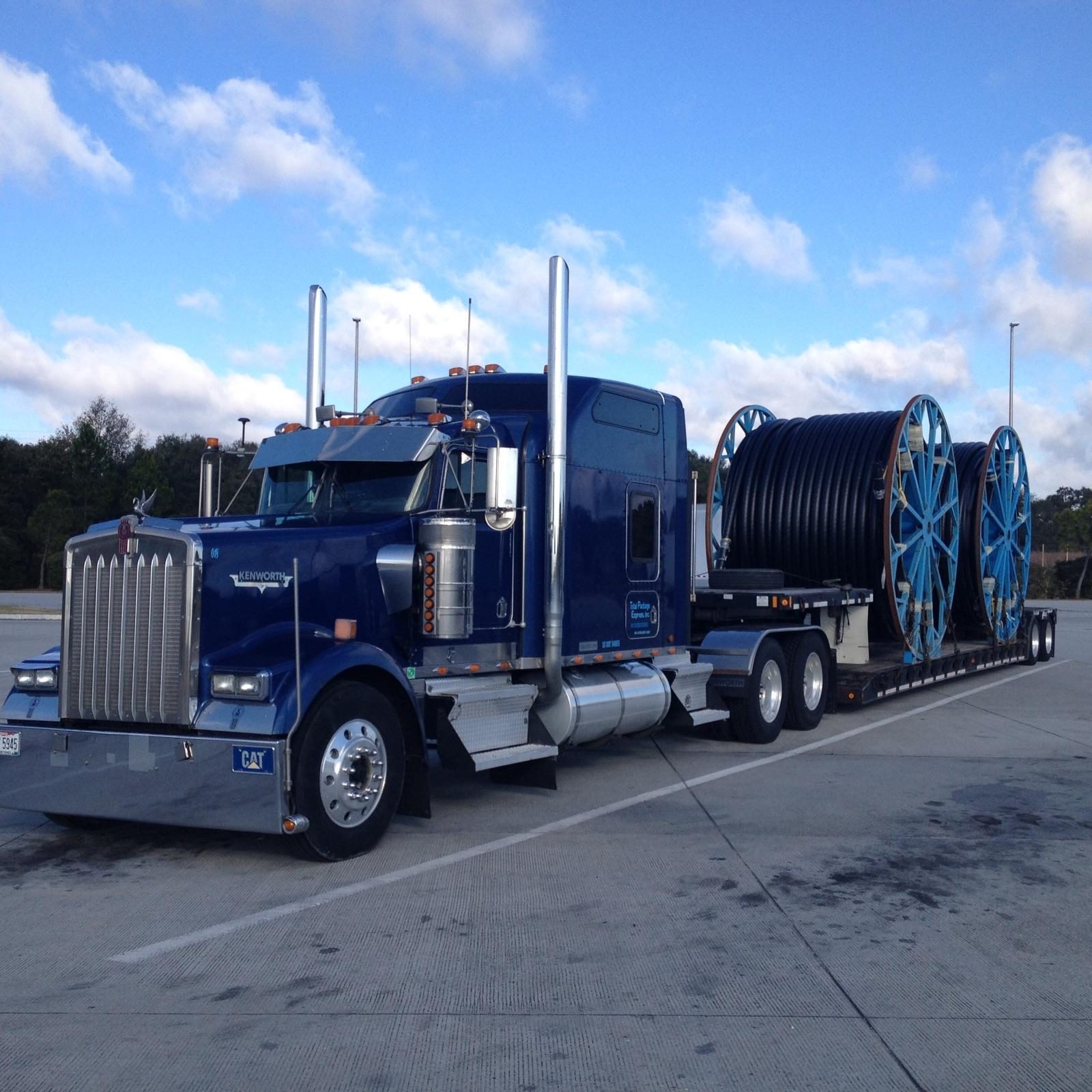 Blue semi truck hauling large cable reels